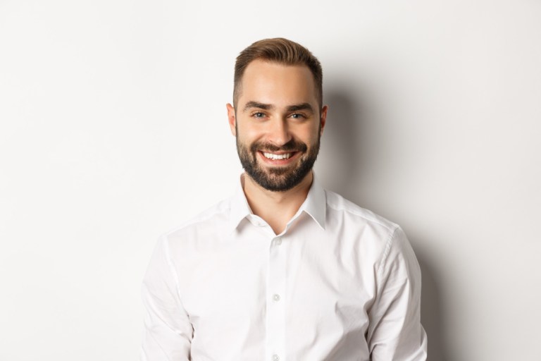 close-up-confident-male-employee-white-collar-shirt-smiling-camera-standing-self-assured-against-studio-background